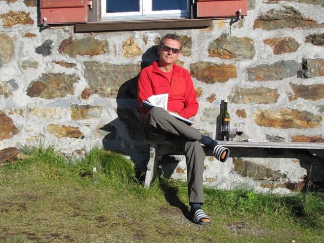 Franco liest das Hüttenbuch, geniesst ein Glas Wein und die Sonne