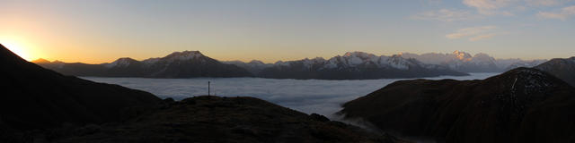 Breitbildfoto Sonnenaufgang. Ganz links erscheint die Sonne. Berninagruppe schon an der Sonne