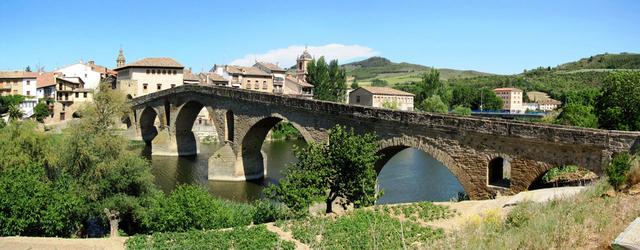 Breitbildfoto der romanischen Puente la Reina die sich mit sechs steinernen Bögen über den Río Arga spannt