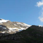 schönes Breitbildfoto. Die Geltenhütte liegt auf einer schönen Alp, umgeben von stiebenden Wasserfällen