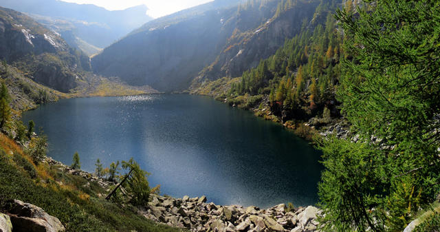 der See spiegelt und wiegelt sich im Sonnenlicht. Tiefblau und vollständig in Gneis eingebettet
