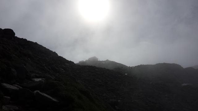 hoch oben leicht verdeckt von den Wolken, taucht die Braunschweigerhütte auf