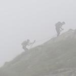 vor uns im Nebel ziehen sich Wanderer an einer Seilsicherung nach oben