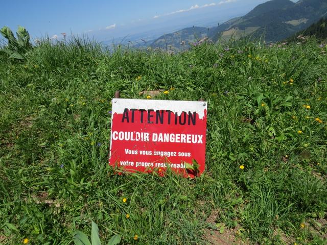 Hinweistafel, das der rechtsabbiegende Wanderweg über ein gefährliches Couloir führt. Betreten auf eigene Gefahr