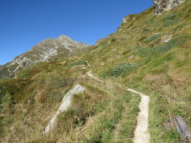 durch Wiesen und unter einer Felswand entlang, folgen wir den nun langsam flacher werdenden Wanderweg