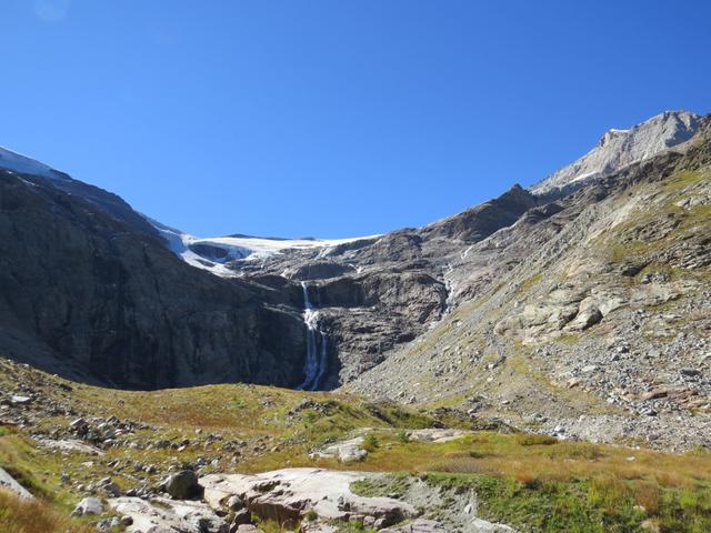 im Sonnenlicht glänzen die Eisflächen hoch über der Felswand