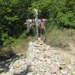 ein von Pilger mit Steinen und anderen Gegenständen umgebenes Kreuz...