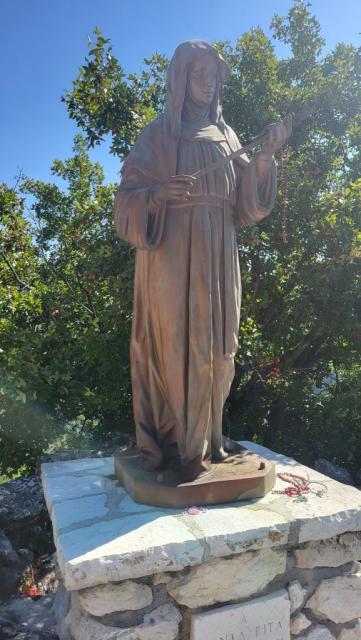 Bronzestatue der hl. Rita die eine Rose in den Händen hält